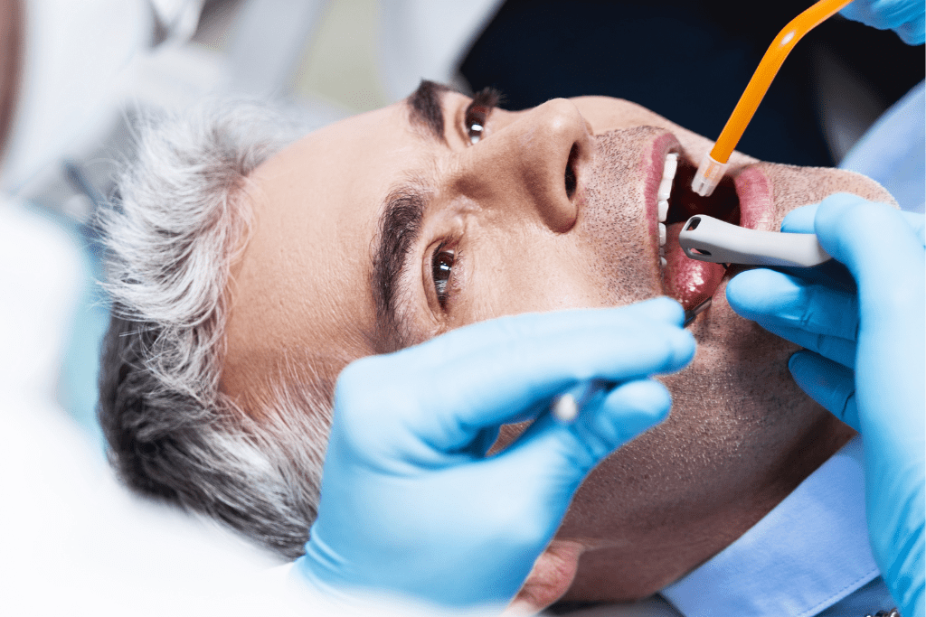 A dentist performing a dental exam to determine if a man needs a root canal or not.